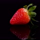 Perfect strawberry rotating on a black polished surface, close up view - VideoHive Item for Sale