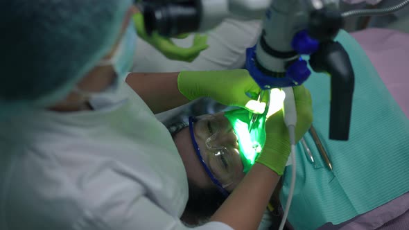 Top View Patient in Dental Chair with Professional Orthodontist Using Dental Microscope Checking