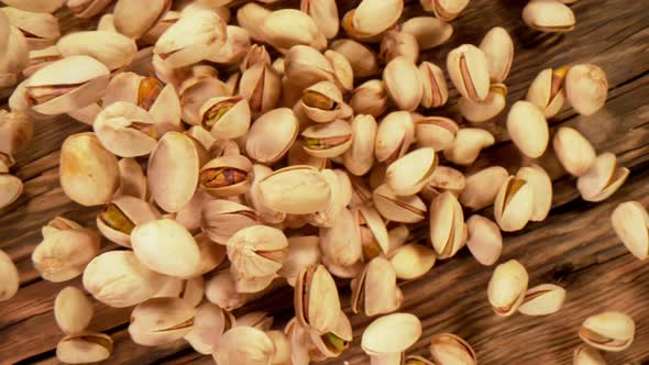 Super Slow Motion Shot of Fresh Roasted Pistachio Nuts Falling on Wooden Table at 1000 Fps