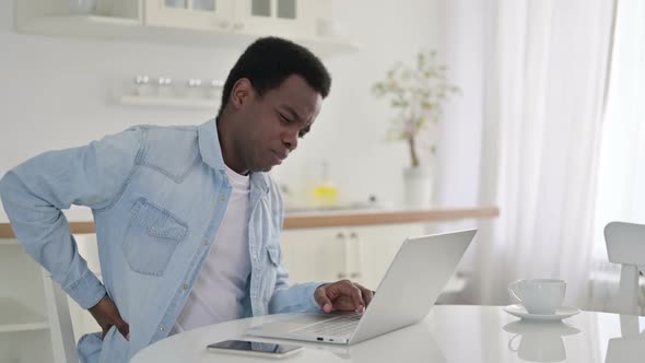 African Man with Laptop Having Back Pain at Home