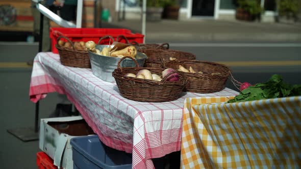 Wide shot of a farmer's market table showing Spring root vegetables like potatoes and parsnips.