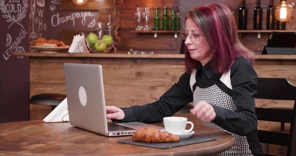 Woman Drinks Coffee While Typing on Laptop Keyboard