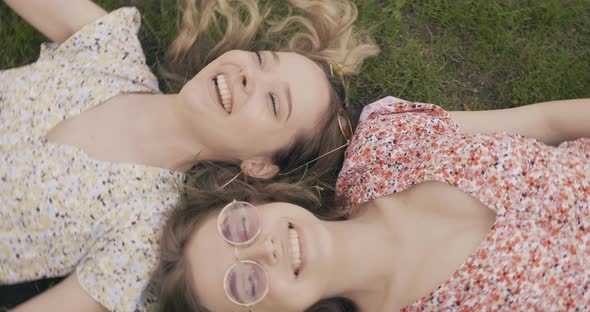 Two young beautiful smiling hipster girls in trendy summer sundress posing outdoors