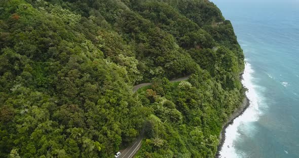 An aerial shot of the road to Hana in Maui. Showcasing the blue coast line beside the lush forestry