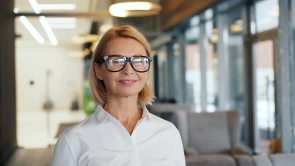 Portrait of Beautiful Senior Businesswoman in Glasses Looking at Camera in Cafe