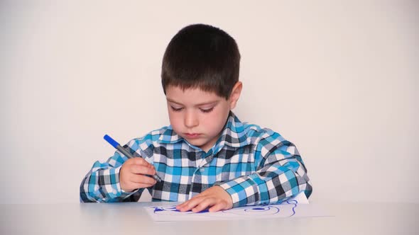 A Preschool Child in a Plaid Shirt Draws a Drawing Paints with a Blue Marker