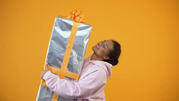 Happy Woman Holding Huge Giftbox on Yellow Background, Surprise, Delivery