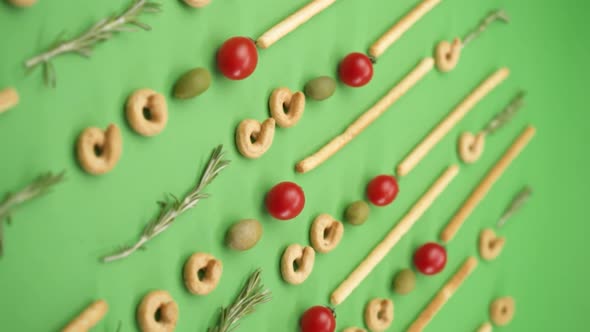 Vertical video: pattern of italian pastries, italian bread sticks, olives, cherry tomatoes, rosemary