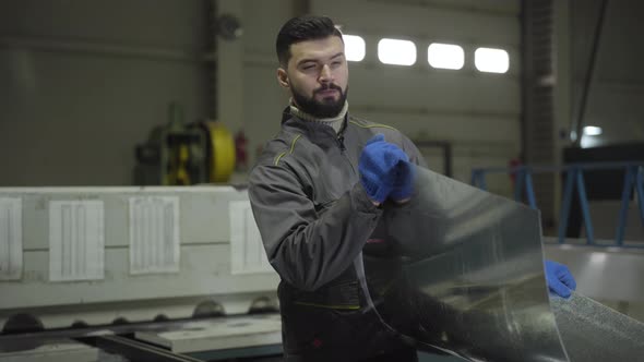 Young Caucasian Man Bending and Looking at Steel Metal Sheet. Professional Worker Visually Checking