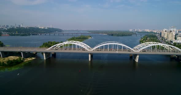 Aerial top view of automobile and railroad Darnitsky bridge across Dnieper river from above