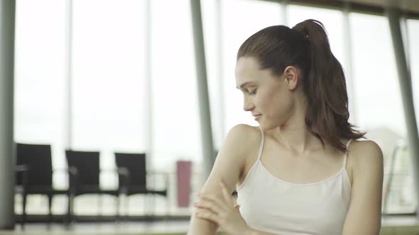 Young woman applying moisturizer to shoulder and arm