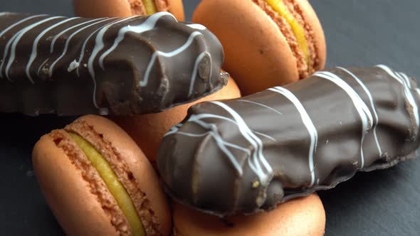 Chocolate and Macaroon Rotate on a Black Background and the Hand Takes Candy Sweets are Spinning