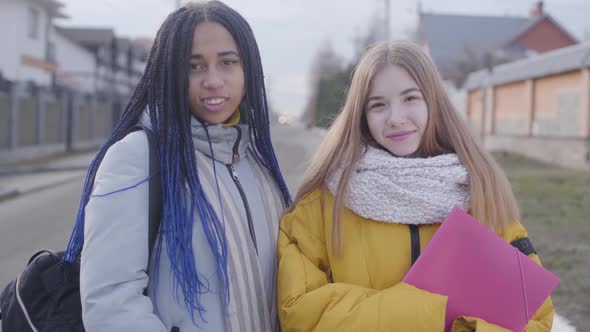 Portrait of Two Beautiful Girls Looking at Camera and Smiling. Caucasian and African American Teens