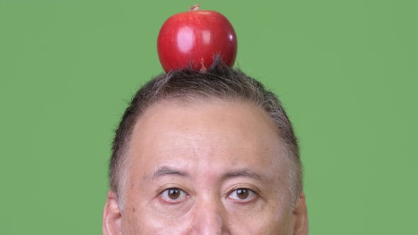 Mature Japanese Businessman with Apple on Head