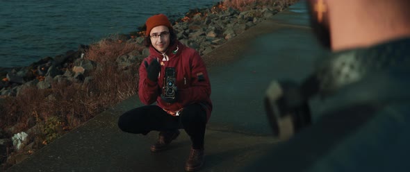 Young man with glasses giving directions to model while he takes shots with vintage camera