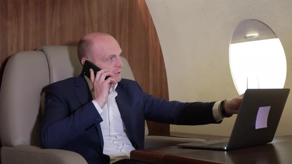 Close Up of a Young Businessman Working at a Computer Talking on the Phone Flying