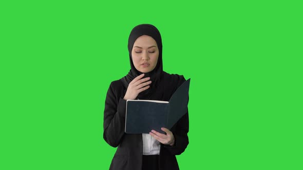 Muslim Businesswoman Reading Her Business Planner While Walking To the Meeting on a Green Screen