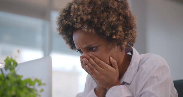 Close Up of Stressed African Businesswoman Covering Face with Hands Reading Report on Laptop