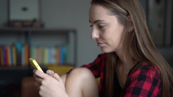 Beautiful young woman writing text message on her smartphone