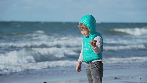 Toddler Boy in Waistcoat Is Playing with Sand on Sea Side.