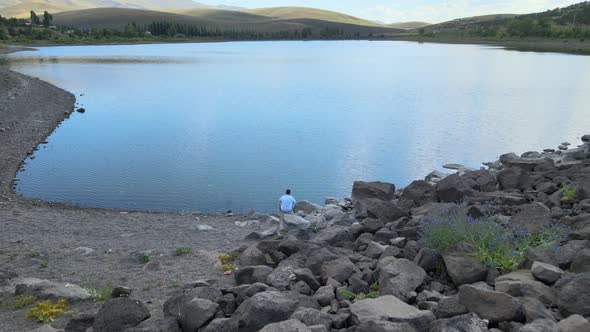 lonely man sitting by the lake