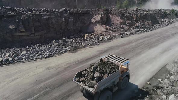 Mining Dump Trucks in Large Granite Open Pit Mine. Close Up Aerial View Drone Chase. Industrial