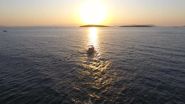 Fishing Boat Sailing at Sunset and Reflection of Evening Sun on the Sea