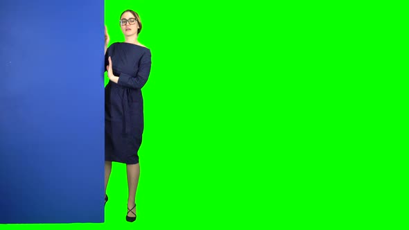 Business Woman Looks Out From Behind a Blue Board and Shows a Okey. Green Screen