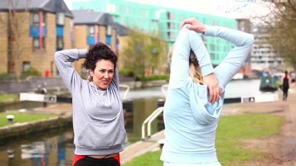 Two girls doing stretching exercises outdoors in London