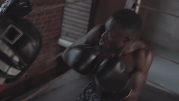 Young Black Boxer Practicing with Coach in Boxing Ring