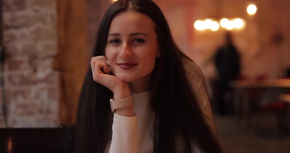 Coquettish Woman Leaning Head on Hand in Cafe