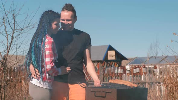 Man and a Woman Cook Burgers on the Grill Together, Hug and Kiss