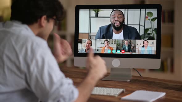 Successful Caucasian Young Man Talking on Video Conference with Colleagues of Different