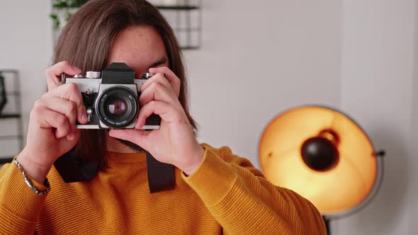 Bearded Caucasian Longhaired Freelancer Guy Taking Photos with His Camera and Looking at Camera with