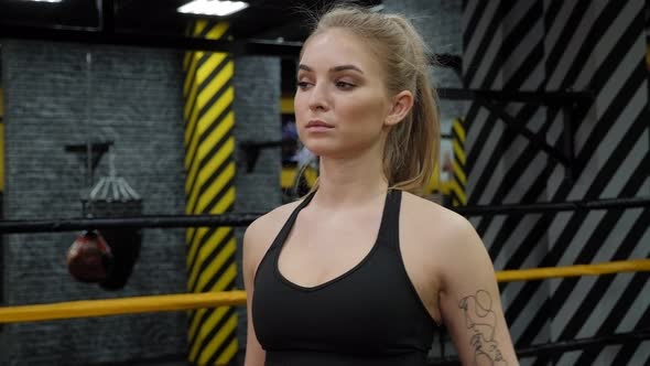 Portrait of a Young Female Kickboxer in the Gym with Black Bandages on Her Hands