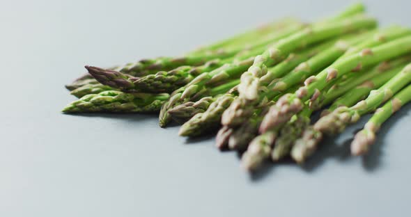 Video of close up of fresh asparagus over grey background