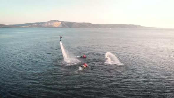 Two Sportsmen Are Lifting Up By Water Flows on Flyboards, Performing Tricks and Plunges, Aerial View