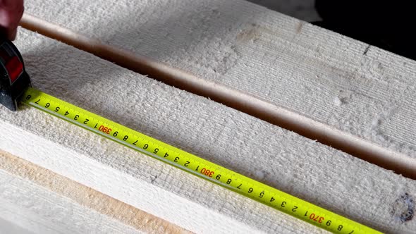 Measuring yellow tape measure scale with centimeters on wooden boards for marking the place of cutti