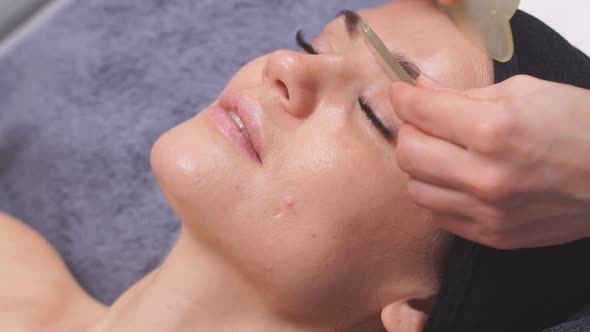 Caucasian Lady Gets Facelift Massage with Gua Sha in Beauty Salon