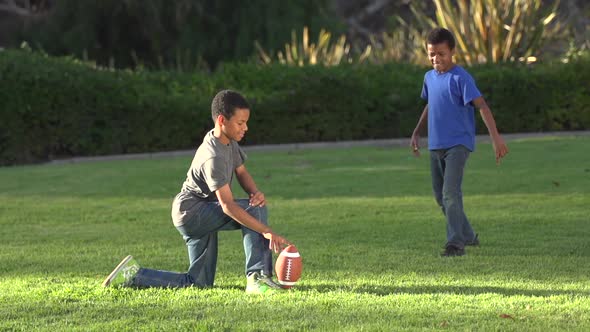 Big brother playing a trick on little brother as he tries to kick a football