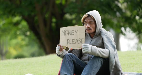 Homeless man sitting and holding money please sign