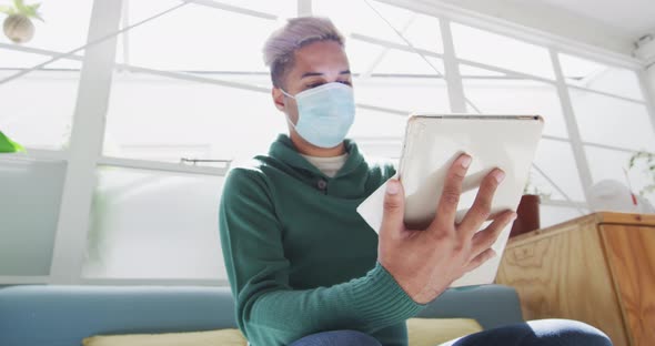 Man wearing face mask wiping his digital tablet with a tissue