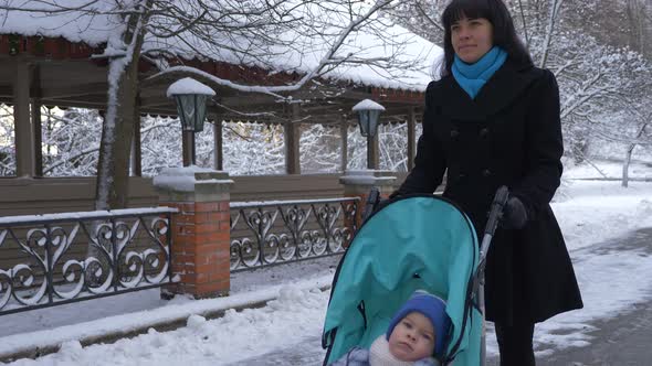 Mother Walks In Park With Her Child In Stroller. Snowy Winter 5