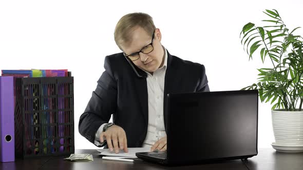 Businessman Working in Office. Talking Loudly on Telephone While Reading Papers