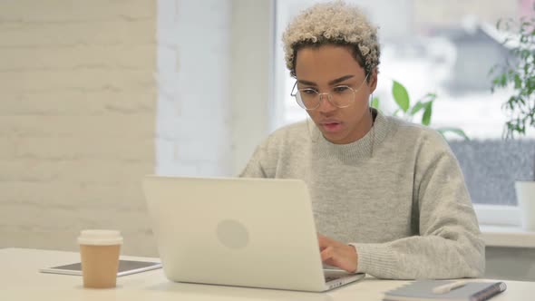 African Woman Celebrating Success While Using Laptop in Office