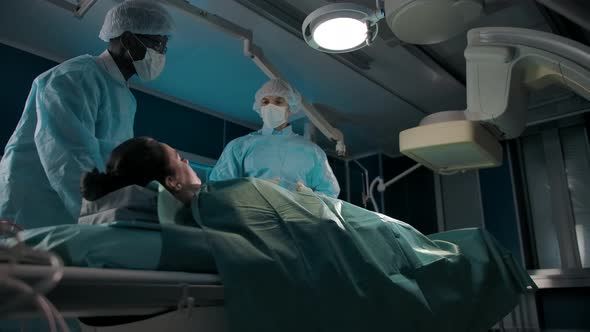 Two Colleagues in the Operating Room Move a Couch with a Female Patient Under an Xray Machine