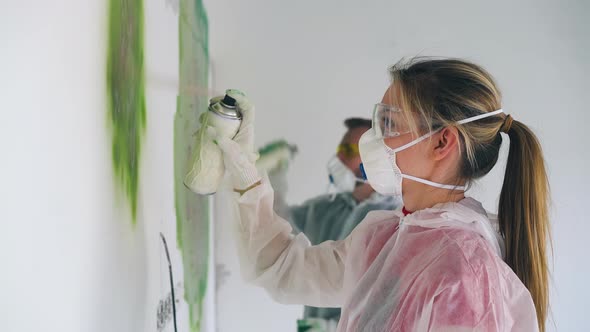 Girl and Boyfriend in Workwears Paint Wall with Green Spray