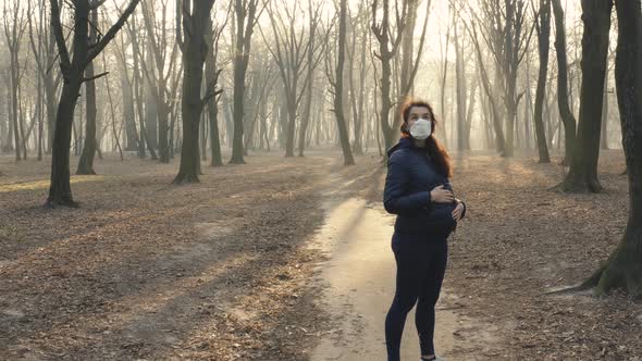 Dolly Stedicam Shot of Pregnant Woman in Face Mask in the Woods. Toxic Smoke or Fog in the Forest at