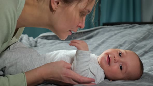 Mother Tickles Newborn Son Making Baby Boy Laugh Loudly