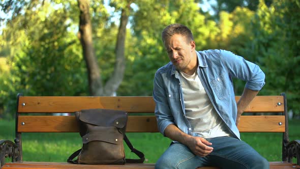 Man Sitting on Bench Suffering From Lover Back Pain After Trauma or Injury